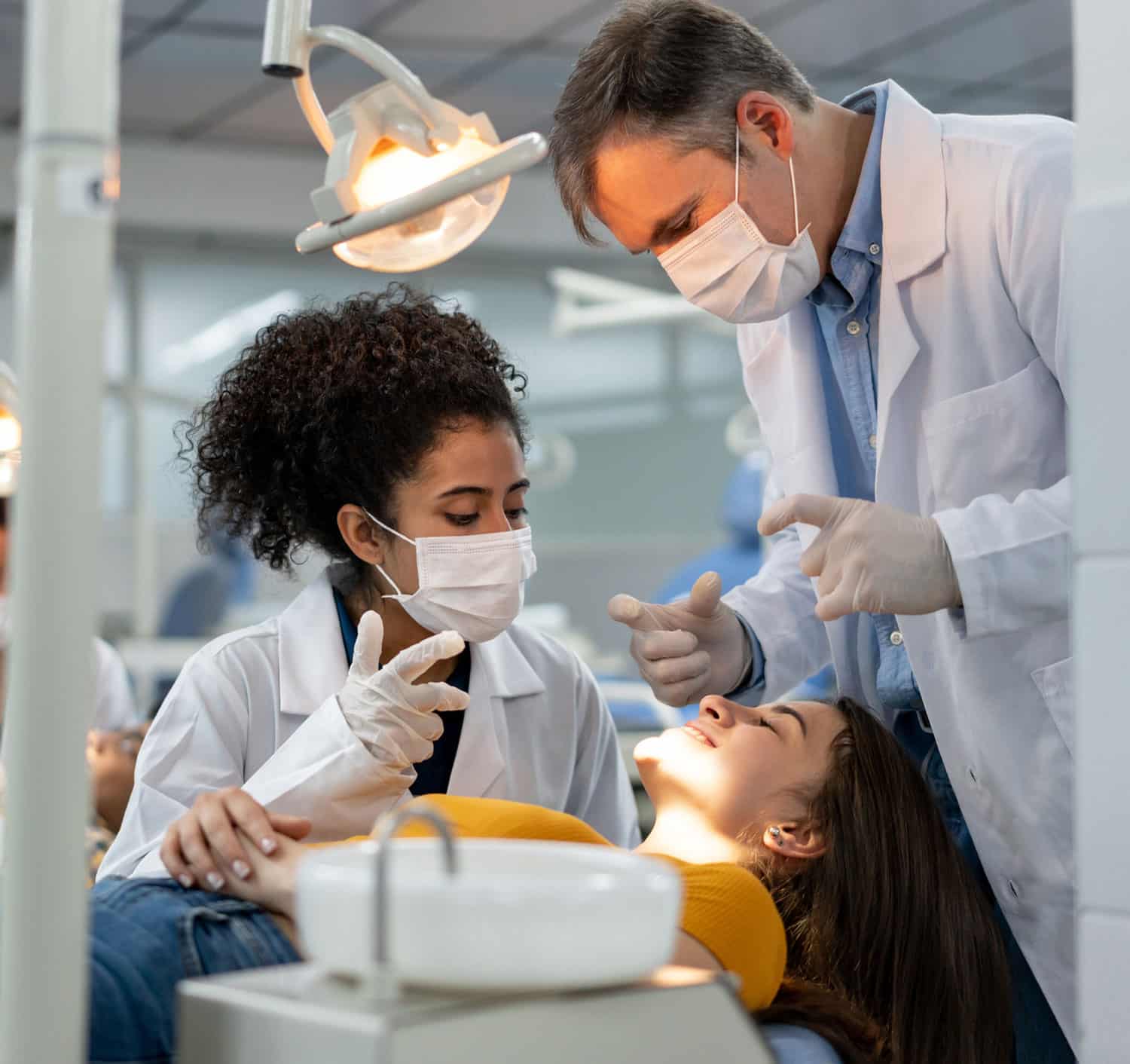 2 dentists talking a patient in the dentist chair